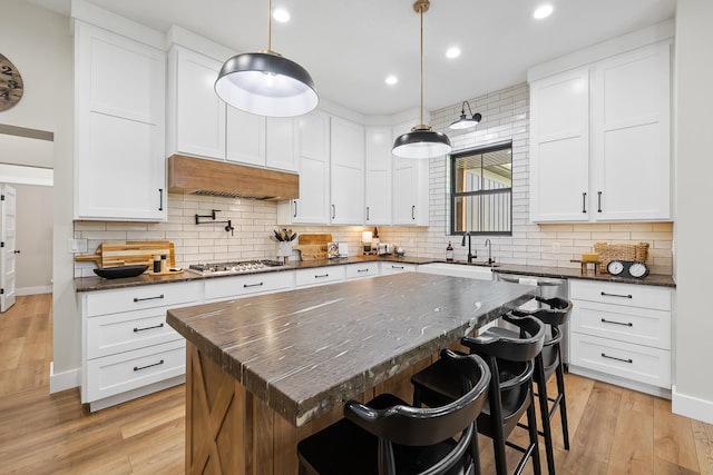 kitchen with light hardwood / wood-style flooring, a center island, backsplash, and custom range hood