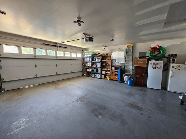 garage featuring white fridge, fridge, and a garage door opener