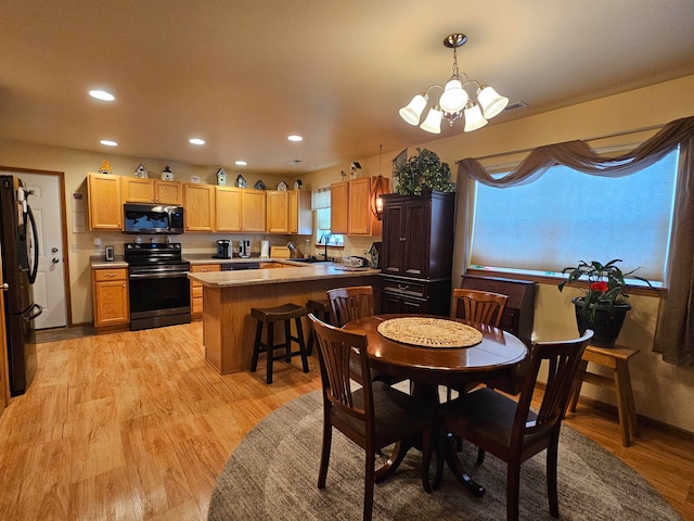 dining room with sink, a chandelier, and light wood-type flooring