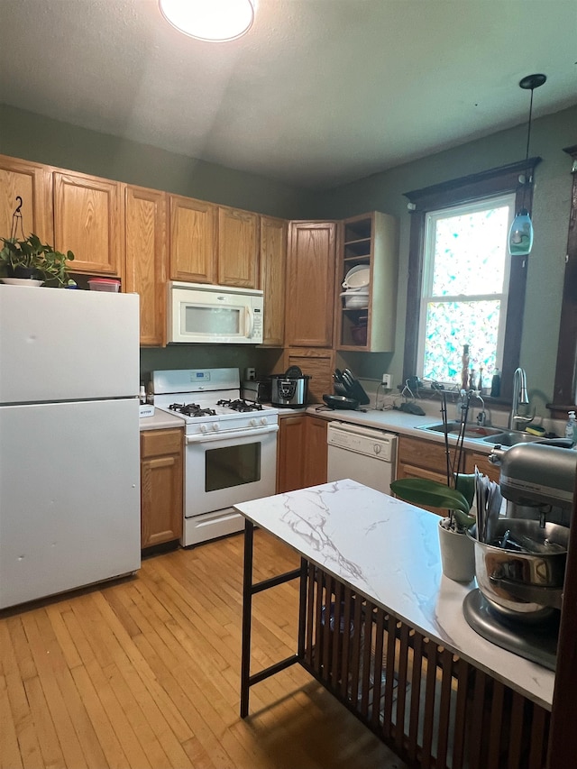 kitchen with sink, light hardwood / wood-style flooring, pendant lighting, and white appliances