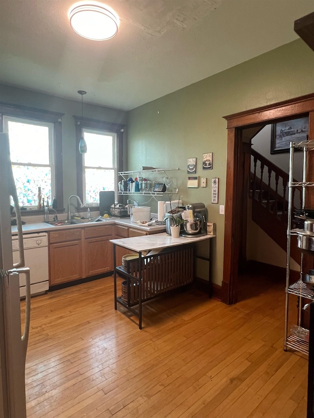 kitchen featuring light wood-type flooring, decorative light fixtures, light brown cabinets, and sink