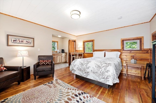 bedroom featuring multiple windows, wood-type flooring, and crown molding