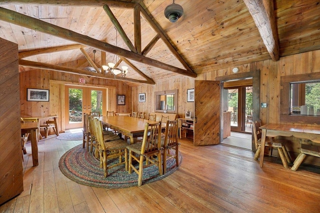 dining room with beam ceiling, french doors, light hardwood / wood-style flooring, and wooden walls