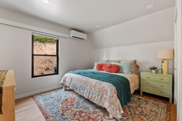 bedroom featuring hardwood / wood-style flooring, vaulted ceiling, and an AC wall unit