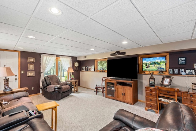 living room with a drop ceiling and light colored carpet