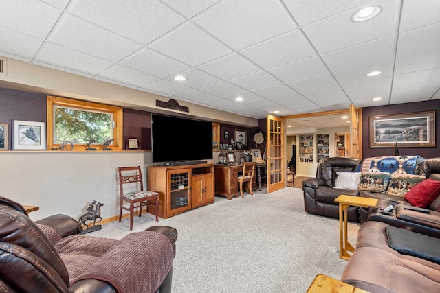 living room with built in features, a paneled ceiling, and light carpet