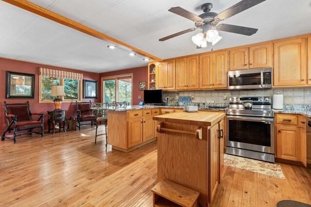 kitchen with appliances with stainless steel finishes, butcher block countertops, tasteful backsplash, and light wood-type flooring