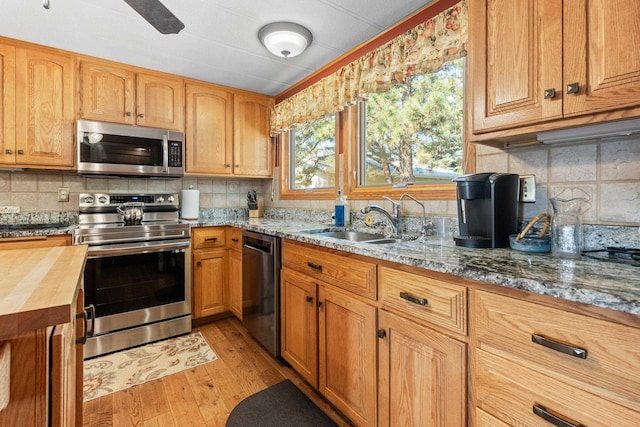 kitchen featuring sink, decorative backsplash, light wood-type flooring, and stainless steel appliances