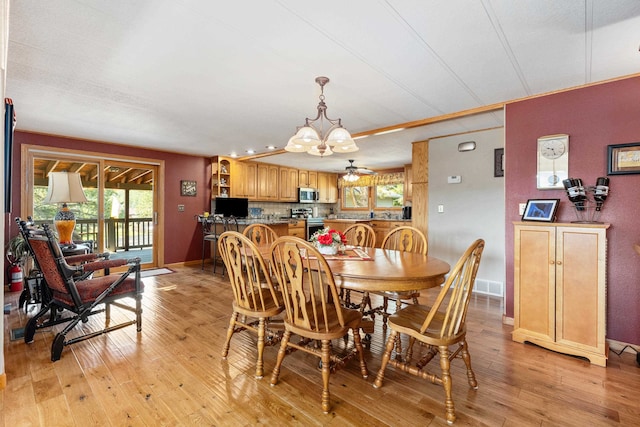 dining room featuring ceiling fan with notable chandelier and light hardwood / wood-style flooring