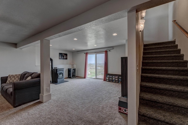 interior space with a textured ceiling, carpet, and a wood stove