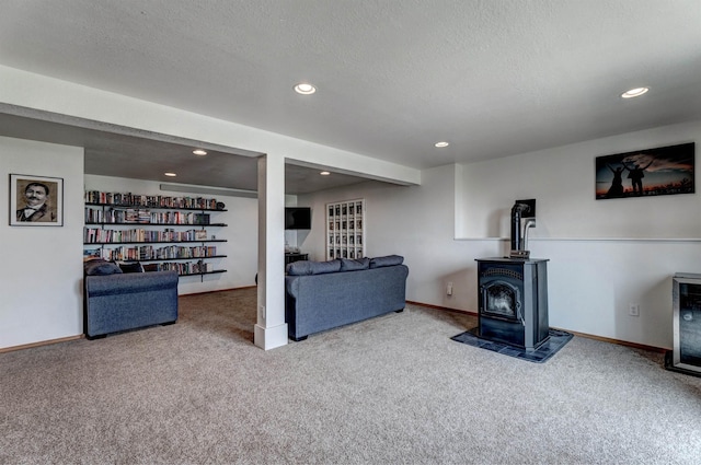 living room featuring carpet, a textured ceiling, and a wood stove