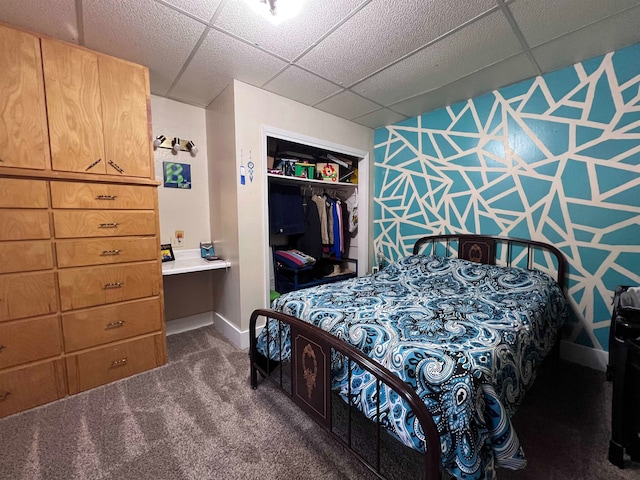 bedroom with dark colored carpet, a closet, and a paneled ceiling