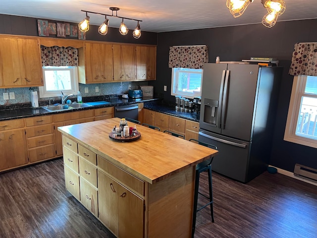 kitchen featuring wooden counters, backsplash, stainless steel refrigerator with ice dispenser, a center island, and dark hardwood / wood-style flooring