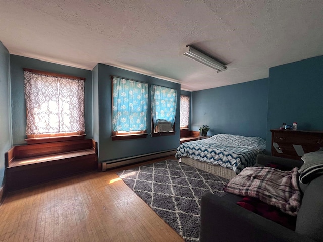 bedroom with a baseboard radiator, cooling unit, a textured ceiling, and wood-type flooring