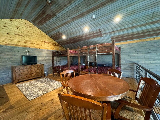 bedroom featuring lofted ceiling with beams, dark colored carpet, wooden walls, and ceiling fan