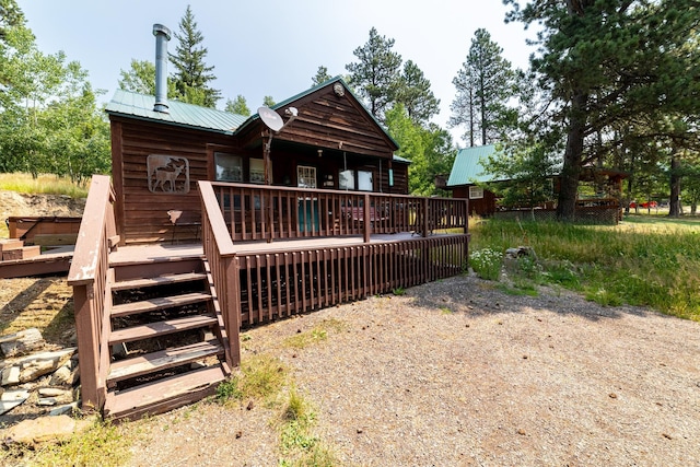 back of property with a deck, driveway, and metal roof