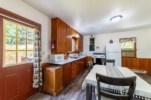 kitchen featuring plenty of natural light, dark hardwood / wood-style floors, a baseboard heating unit, and white appliances