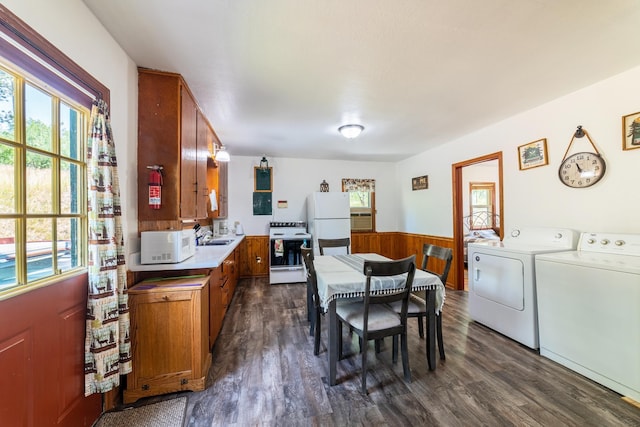 kitchen with dark wood-type flooring, washing machine and dryer, white appliances, brown cabinetry, and wainscoting
