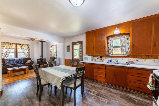 kitchen with white appliances, a wood stove, light countertops, and a sink