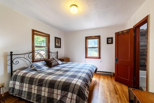 bedroom featuring a baseboard radiator, light wood-type flooring, and a textured ceiling