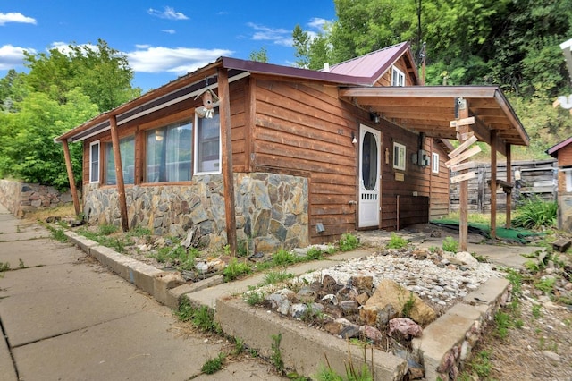 view of side of home with stone siding and metal roof