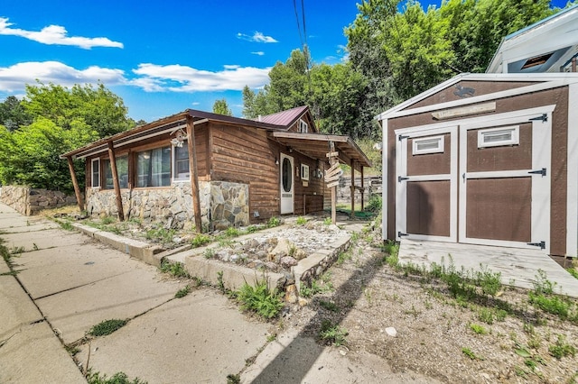 view of side of home featuring an outbuilding, metal roof, and a storage shed