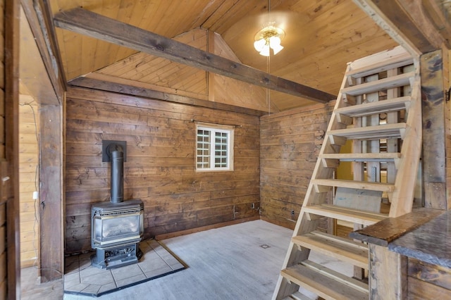 unfurnished living room featuring wood ceiling, lofted ceiling with beams, light hardwood / wood-style floors, a wood stove, and wood walls