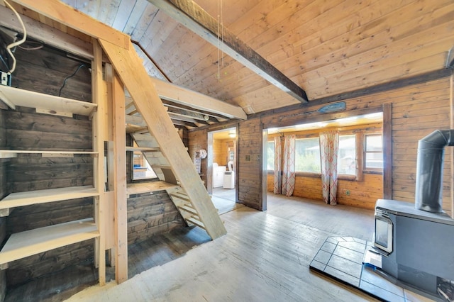 interior space featuring wood-type flooring, vaulted ceiling with beams, a wood stove, and wooden walls