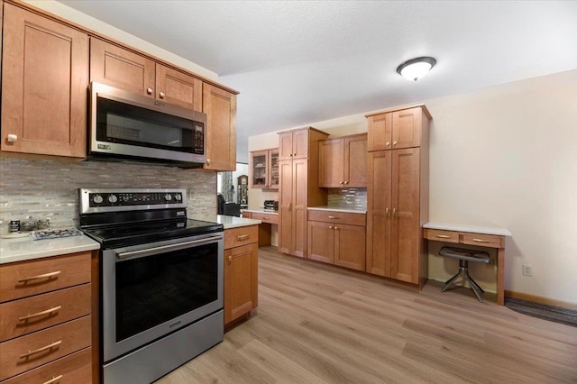 kitchen featuring stainless steel appliances, tasteful backsplash, and light wood-type flooring