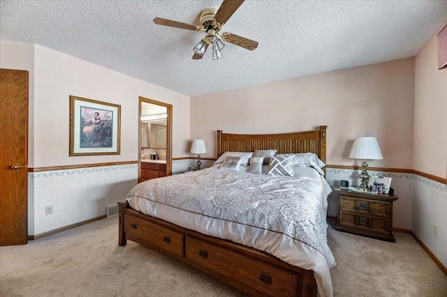 bedroom with ceiling fan, light colored carpet, and a textured ceiling