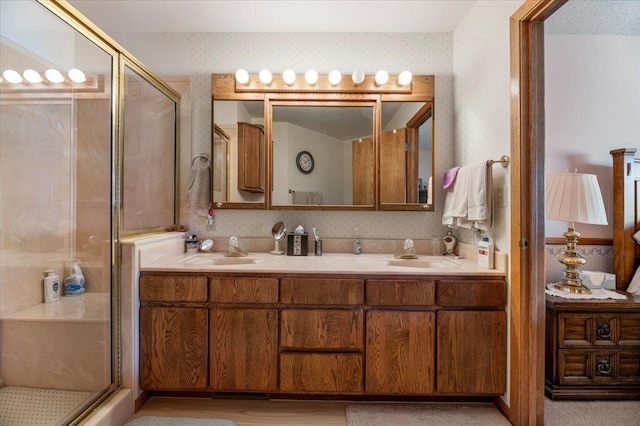 bathroom featuring a shower with door and double sink vanity