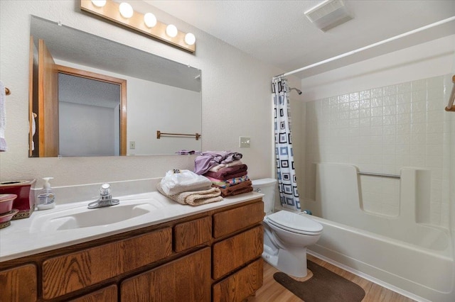 full bathroom with shower / bath combo with shower curtain, a textured ceiling, toilet, vanity, and hardwood / wood-style flooring