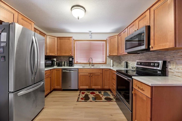 kitchen with sink, light hardwood / wood-style flooring, stainless steel appliances, and tasteful backsplash