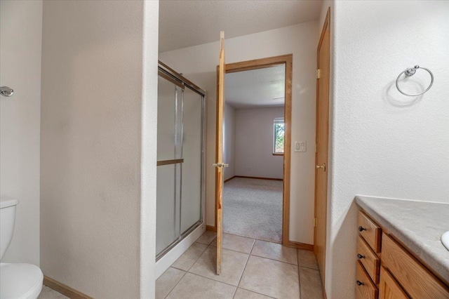 bathroom with vanity, tile patterned flooring, a shower with door, and toilet