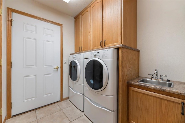 clothes washing area with cabinets, washing machine and dryer, sink, and light tile patterned floors