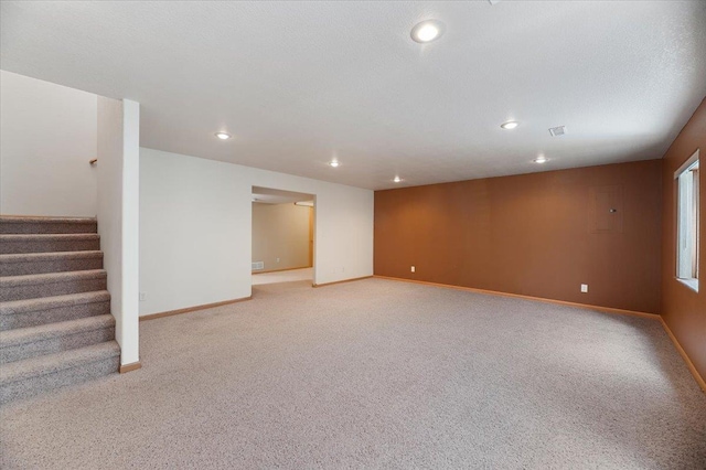 basement featuring light carpet and a textured ceiling