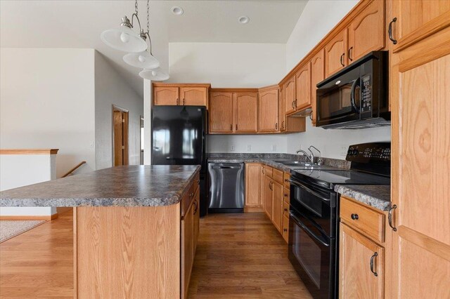 kitchen featuring a center island, dark hardwood / wood-style floors, black appliances, hanging light fixtures, and sink