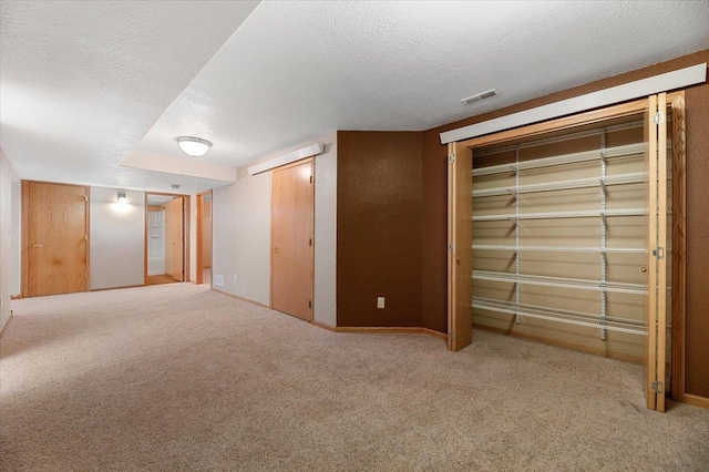 interior space featuring light colored carpet and a textured ceiling