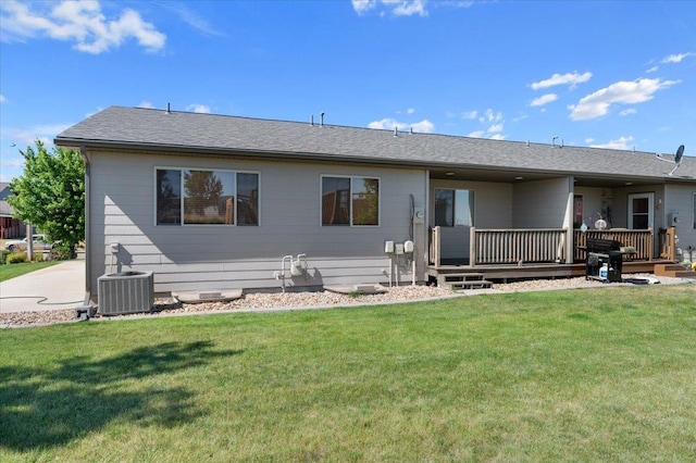 rear view of property featuring central AC, covered porch, and a lawn