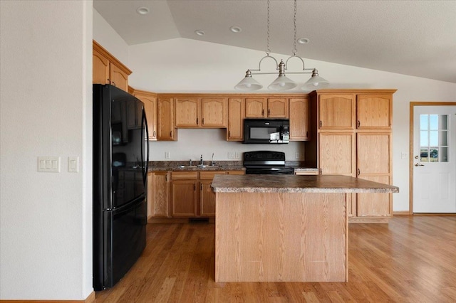 kitchen featuring lofted ceiling, sink, a center island, wood-type flooring, and black appliances