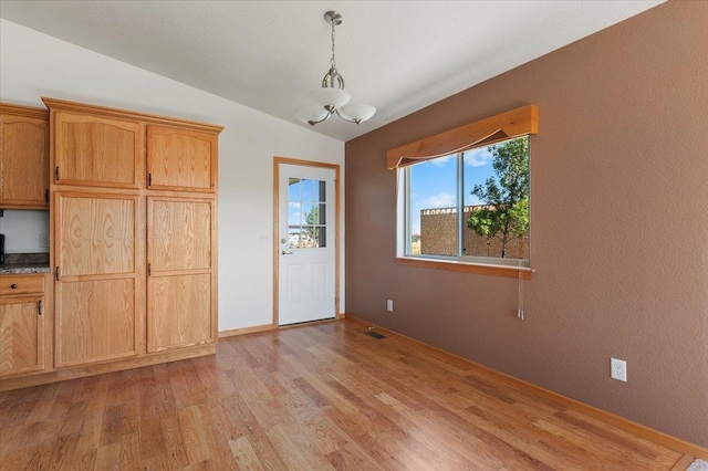 unfurnished dining area featuring lofted ceiling and light wood-type flooring