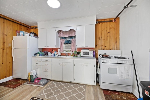 kitchen featuring white cabinetry, white appliances, wood walls, light hardwood / wood-style floors, and sink