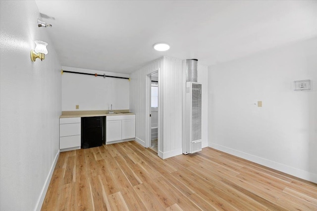 bar featuring sink, light hardwood / wood-style flooring, and white cabinets