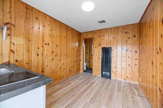 spare room featuring light hardwood / wood-style flooring and wooden walls