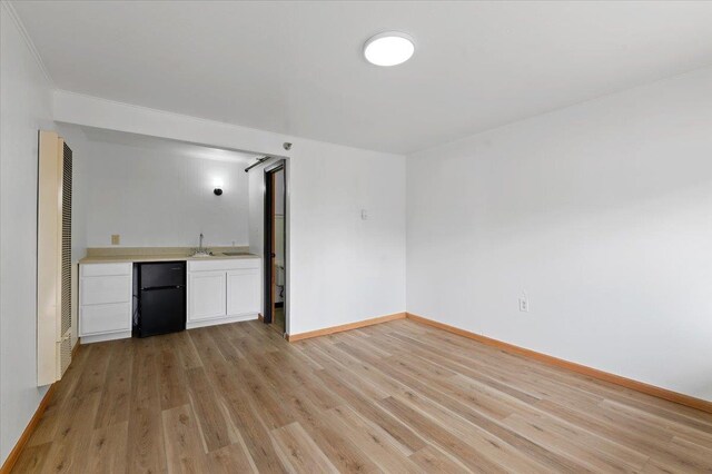 230 N Main St, Spearfish, SD 57783 - unfurnished living room featuring wet bar, light wood finished floors, baseboards, and a heating unit