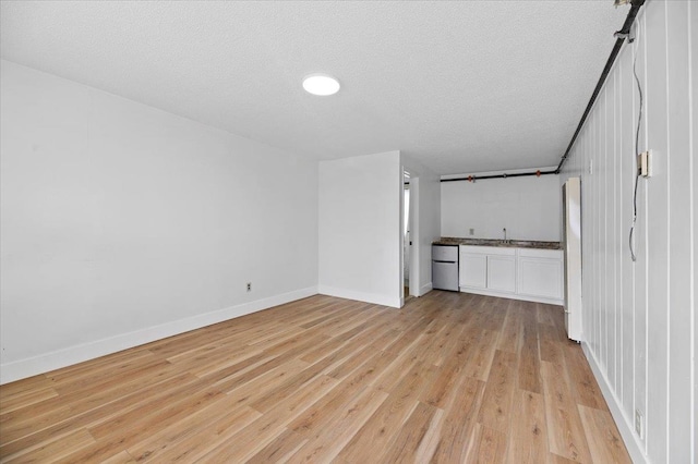 unfurnished bedroom featuring sink, a textured ceiling, and light wood-type flooring