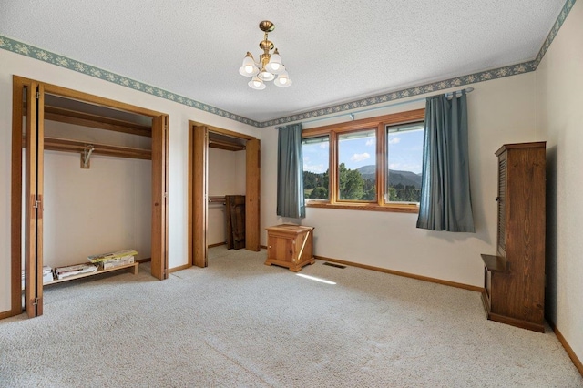 unfurnished bedroom featuring carpet, a textured ceiling, and an inviting chandelier