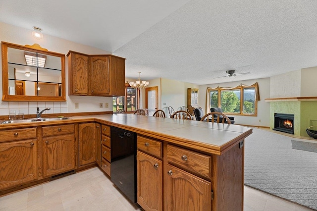 kitchen with kitchen peninsula, dishwasher, light colored carpet, a fireplace, and sink