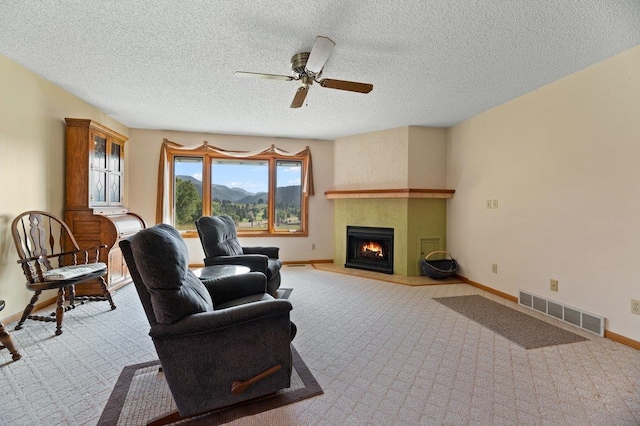 carpeted living room with ceiling fan, a fireplace, and a textured ceiling