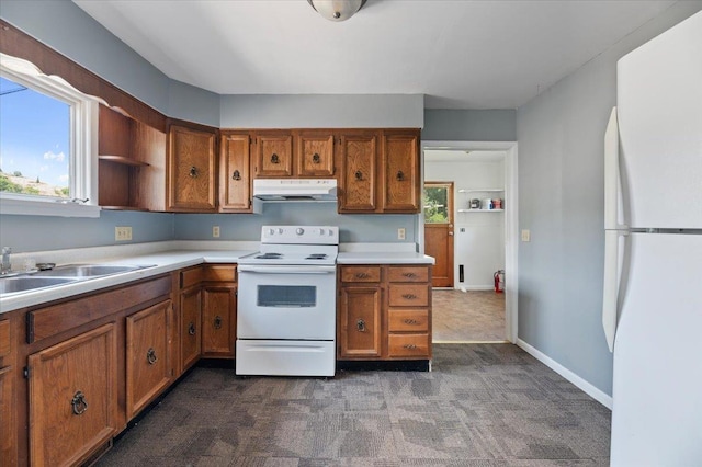 kitchen with white appliances, sink, and dark carpet